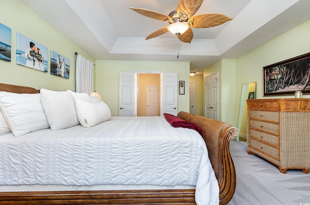 bedroom featuring ceiling fan, carpet flooring, and a raised ceiling