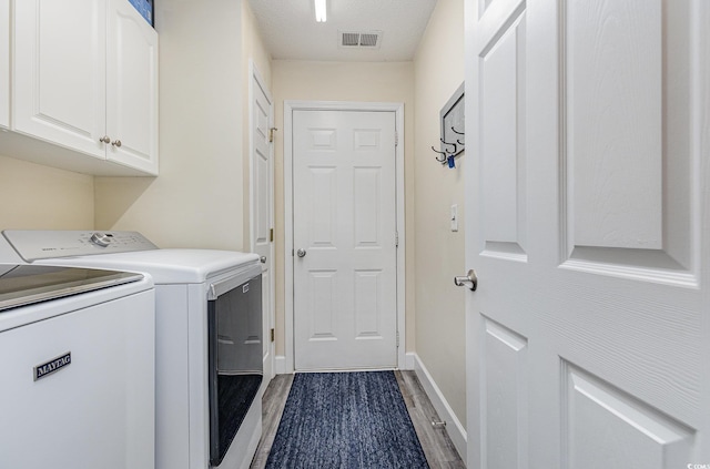 laundry area featuring cabinets, separate washer and dryer, a textured ceiling, and hardwood / wood-style floors