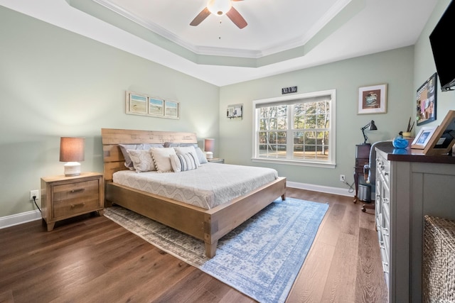 bedroom with ceiling fan, dark wood-type flooring, a tray ceiling, and ornamental molding