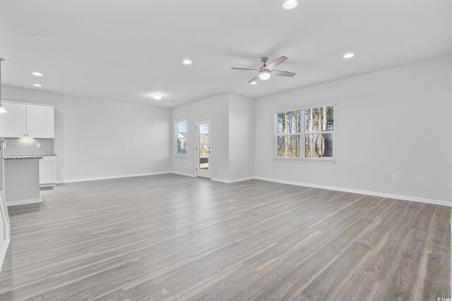 kitchen featuring white cabinets, stainless steel appliances, hanging light fixtures, and a center island with sink