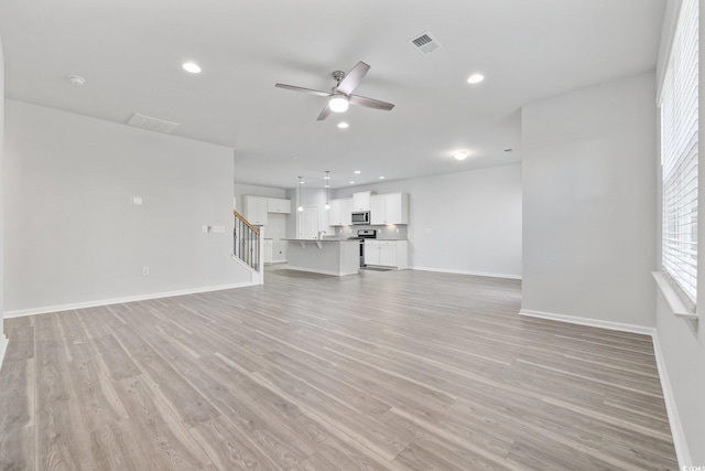 unfurnished living room with ceiling fan and light hardwood / wood-style flooring