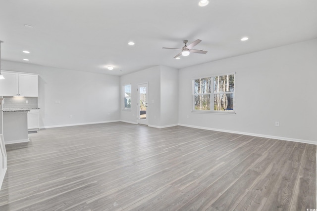 unfurnished living room featuring ceiling fan and light hardwood / wood-style floors