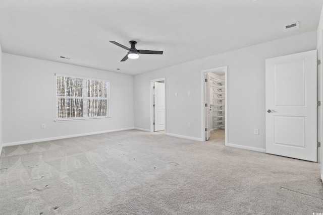 unfurnished bedroom featuring ceiling fan, a walk in closet, and light carpet