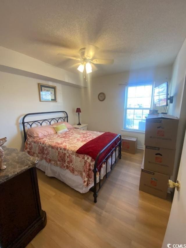 8650 Southbridge Dr Unit A, Surfside Beach, SC 29575 - bedroom with light wood finished floors, a textured ceiling, and ceiling fan