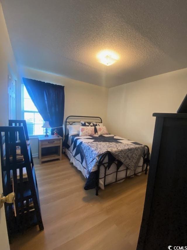 8650 Southbridge Dr Unit A, Surfside Beach, SC 29575 - bedroom with light wood-style floors and a textured ceiling