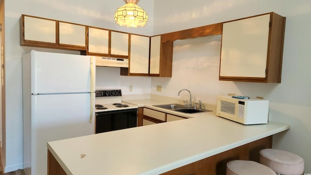 kitchen with decorative light fixtures, sink, kitchen peninsula, and white appliances