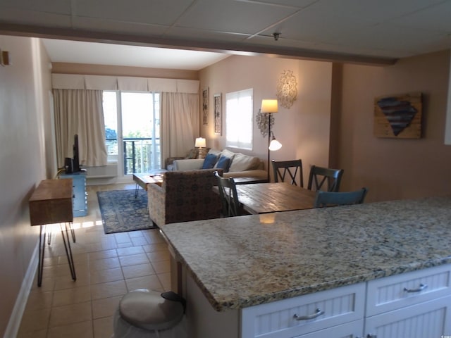 kitchen featuring light tile patterned floors, light stone counters, white cabinets, and open floor plan