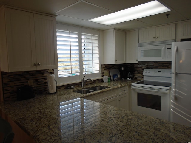 kitchen featuring light stone counters, white appliances, a sink, and backsplash