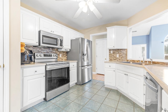 kitchen with light tile patterned floors, stainless steel appliances, tasteful backsplash, white cabinets, and sink