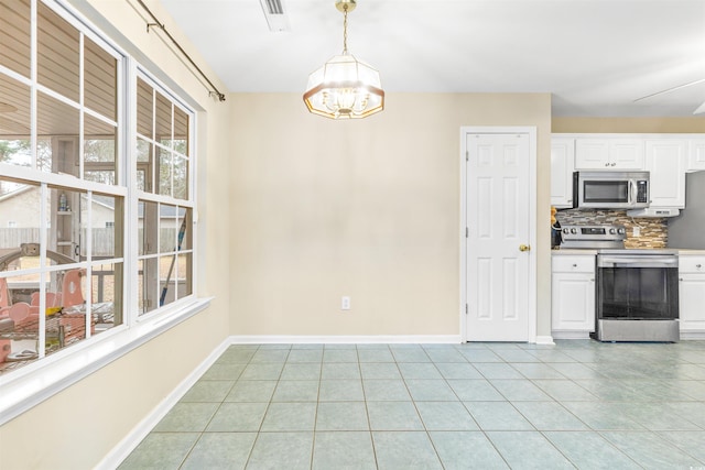 kitchen with appliances with stainless steel finishes, decorative backsplash, hanging light fixtures, a wealth of natural light, and white cabinets