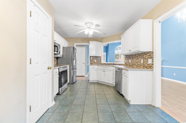 kitchen with light tile patterned floors, ceiling fan, appliances with stainless steel finishes, decorative backsplash, and white cabinets