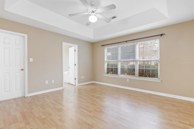 spare room with ceiling fan, light hardwood / wood-style flooring, and a tray ceiling