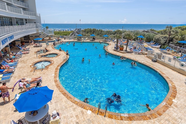 view of swimming pool with a water view, a hot tub, and a patio