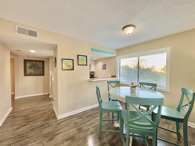 dining area with dark wood-type flooring and a textured ceiling