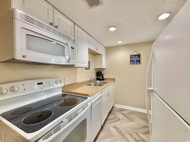 kitchen with sink, white appliances, white cabinets, and a textured ceiling