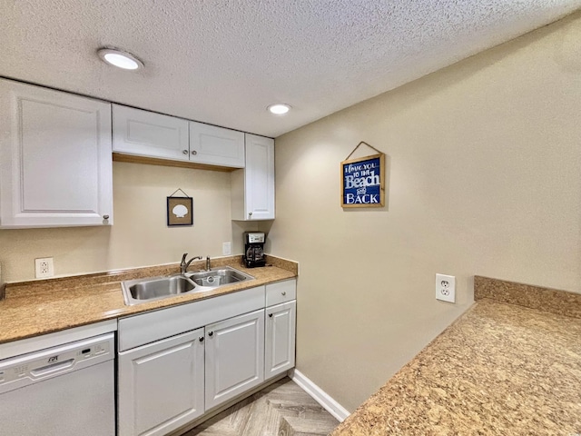 kitchen with sink, white dishwasher, white cabinetry, and a textured ceiling