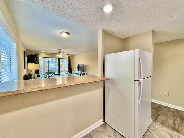 kitchen with a textured ceiling, ceiling fan, and white refrigerator