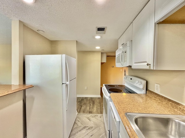 kitchen featuring a textured ceiling, sink, white cabinets, and white appliances