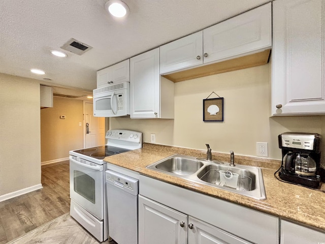 kitchen with white appliances, white cabinets, a textured ceiling, sink, and light wood-type flooring