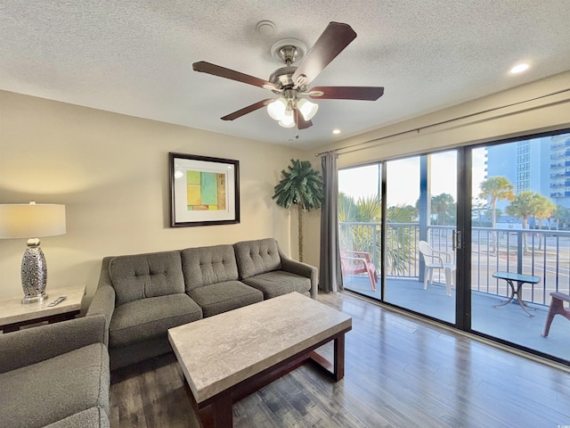 living room featuring ceiling fan, a textured ceiling, and hardwood / wood-style flooring