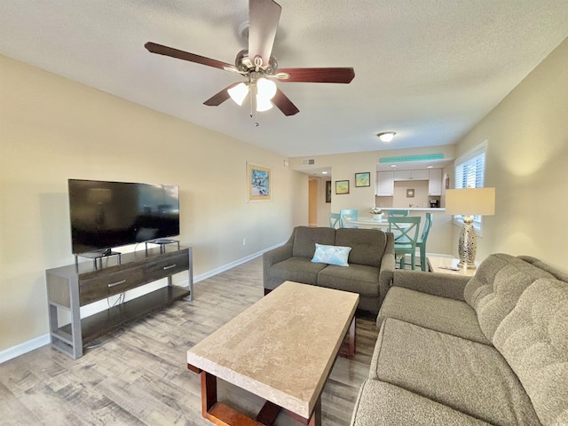 living room with a textured ceiling, ceiling fan, and hardwood / wood-style floors