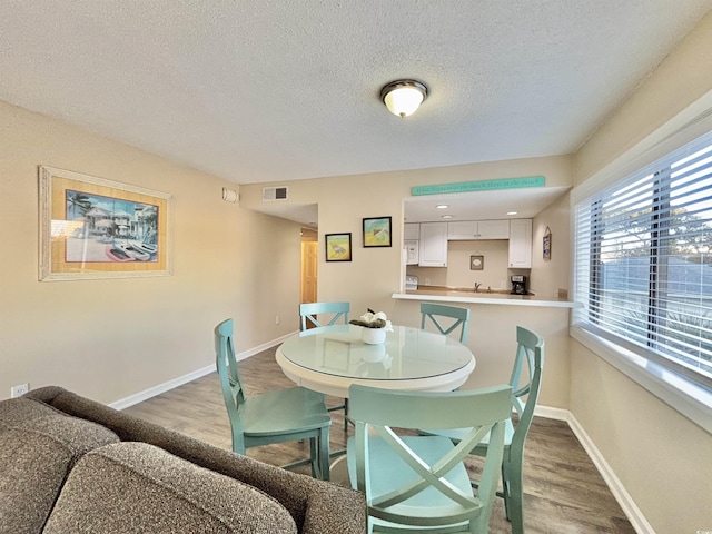 dining area with a textured ceiling and hardwood / wood-style floors