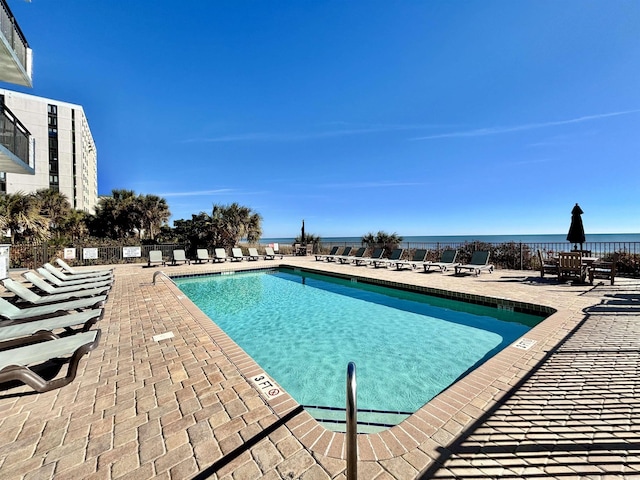 view of swimming pool with a water view and a patio