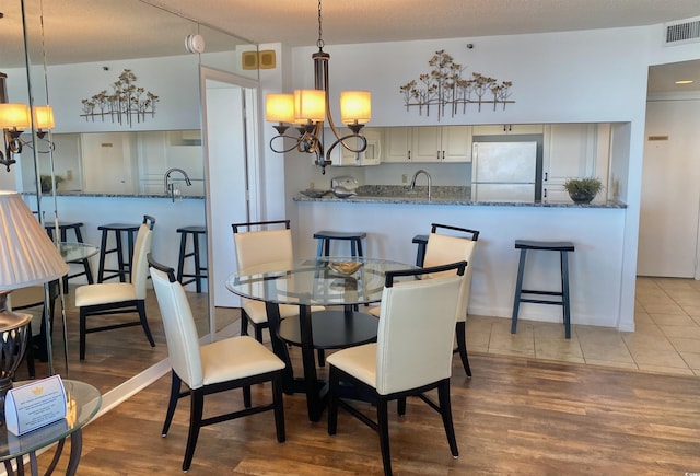 dining area with sink, a textured ceiling, and light hardwood / wood-style flooring