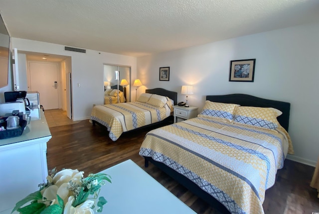 bedroom featuring a closet, dark hardwood / wood-style floors, and a textured ceiling