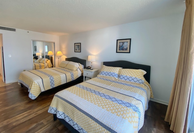 bedroom with a textured ceiling, a closet, and dark hardwood / wood-style flooring