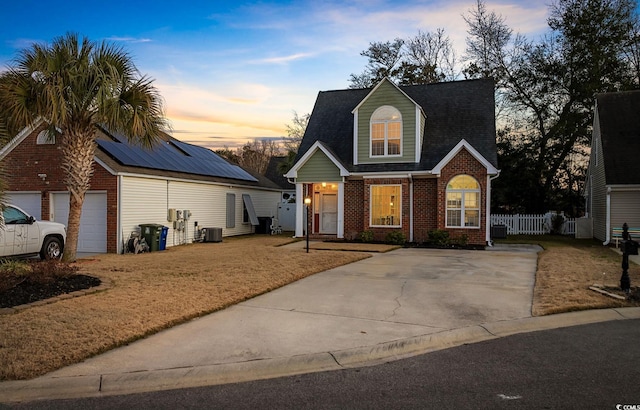 view of front of property featuring cooling unit, a garage, and solar panels