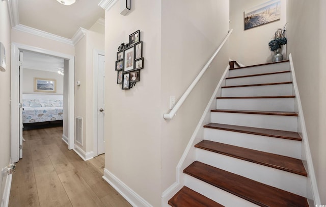 stairs with crown molding and hardwood / wood-style floors