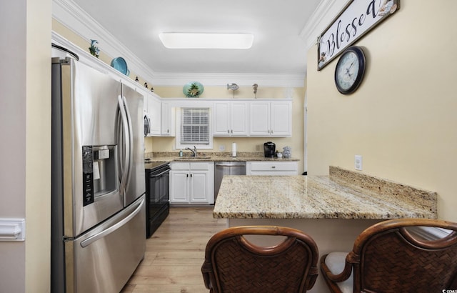 kitchen with a breakfast bar, appliances with stainless steel finishes, white cabinetry, light stone counters, and kitchen peninsula