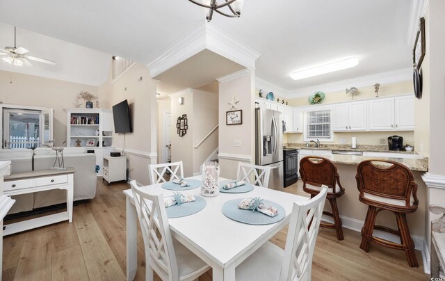 dining room with sink, ornamental molding, ceiling fan, and light wood-type flooring