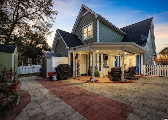 back house at dusk with a storage unit and a patio area