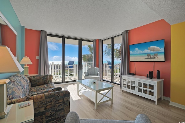 living room featuring a wall of windows, light hardwood / wood-style flooring, and a textured ceiling