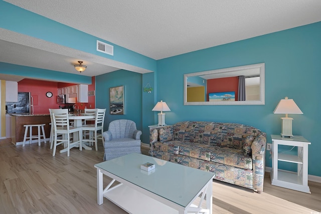 living room with a textured ceiling and light wood-type flooring