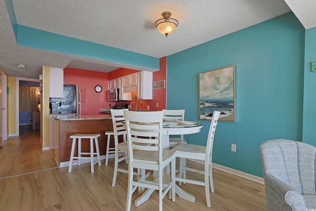 dining room with light hardwood / wood-style flooring and a textured ceiling