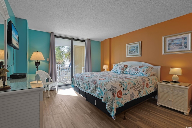 bedroom with a textured ceiling, access to outside, floor to ceiling windows, and wood-type flooring