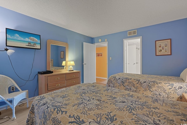 bedroom featuring light hardwood / wood-style floors and a textured ceiling