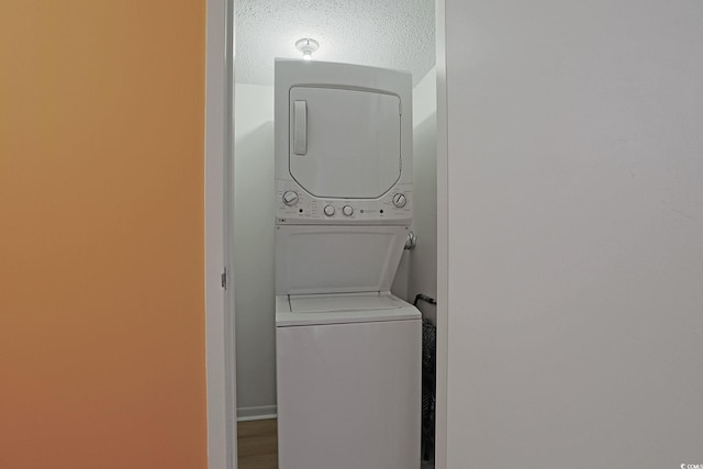 laundry room with stacked washer / dryer and a textured ceiling