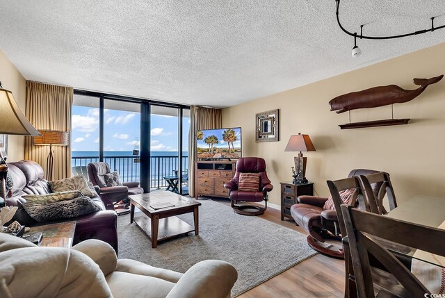 living room with a textured ceiling, expansive windows, and light hardwood / wood-style flooring