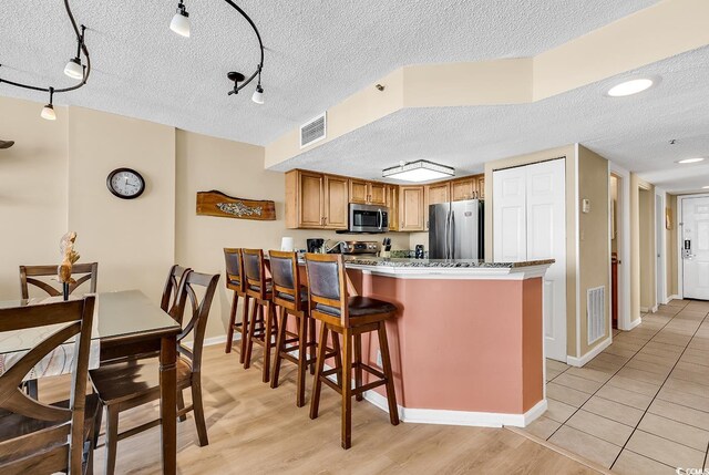 kitchen featuring light stone counters, sink, a textured ceiling, and stainless steel appliances