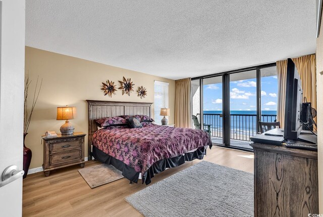 bedroom with access to exterior, a textured ceiling, and a wall of windows