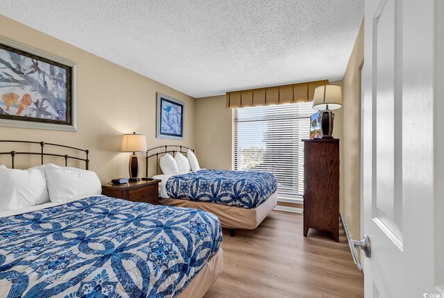 bedroom with light wood-type flooring and a textured ceiling