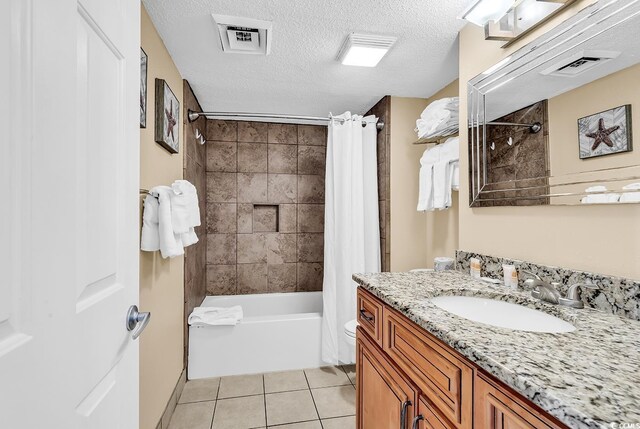 bathroom with vanity, shower / tub combo with curtain, tile patterned floors, and a textured ceiling