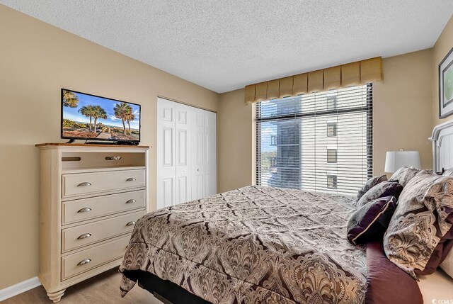 bedroom featuring a closet, a textured ceiling, and light hardwood / wood-style flooring