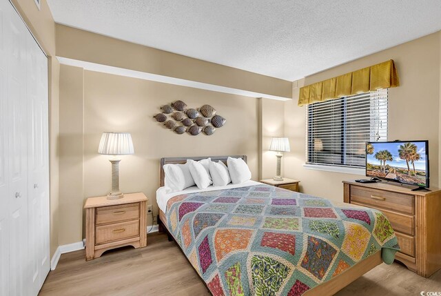 bedroom featuring a textured ceiling, a closet, and light hardwood / wood-style floors