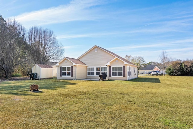 single story home featuring an outdoor fire pit, a front lawn, and a storage unit