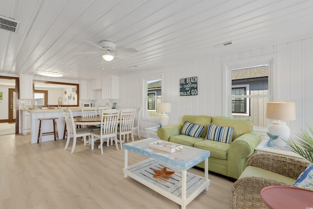 living room with light wood-type flooring, wooden ceiling, plenty of natural light, and ceiling fan